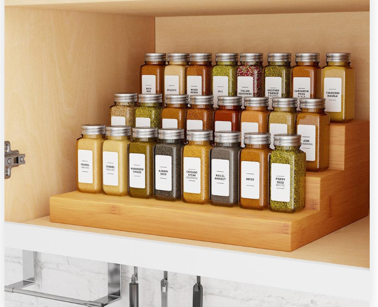 Tiered spice rack inside kitchen cabinet with visible labeled jars